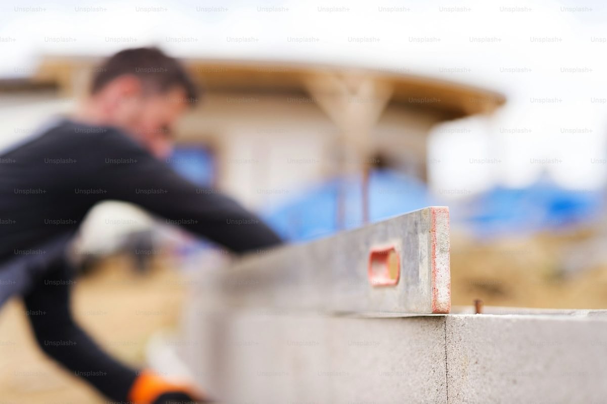 Concreter laying a besser block on a new wall course